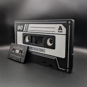 Oversized black and white retro cassette tape with optional LED nightlight feature, next to a standard-sized cassette for scale