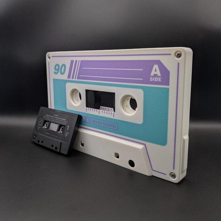 White oversized retro cassette with purple and teal details, optional LED lightbox feature, shown next to a regular black cassette for scale