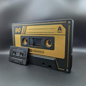 Gigantic retro gold and black cassette tape lightbox, vintage-style music decor with optional LED nightlight, shown next to a standard cassette tape for size reference