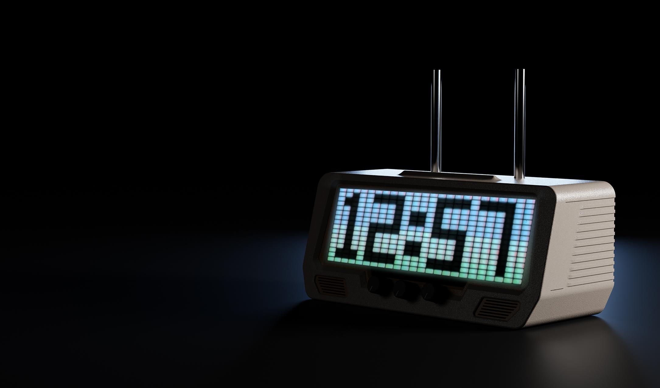 A digital clock with an illuminated pixel-style display showing 12:57, set against a dark, modern background with audio equipment.