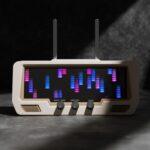 The Audio Visualizer Pro, a beige device with twin antennas, displays a vibrant LED spectrum analyzer and has three rotary dials: Modes/Menu, Amplitude, and Colors.