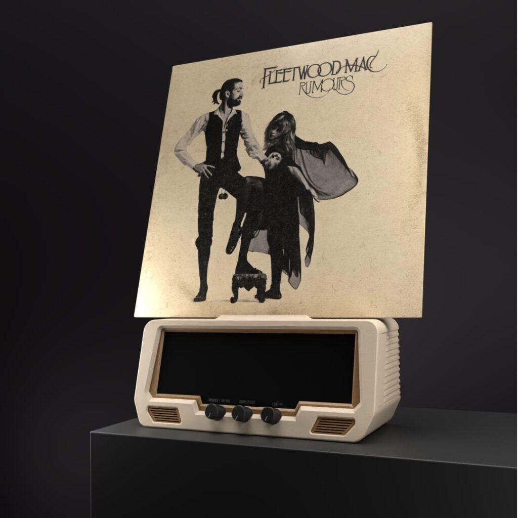 A Fleetwood Mac Rumours vinyl record is propped upright on a retro hi-fi radio receiver resting on a dark tabletop.