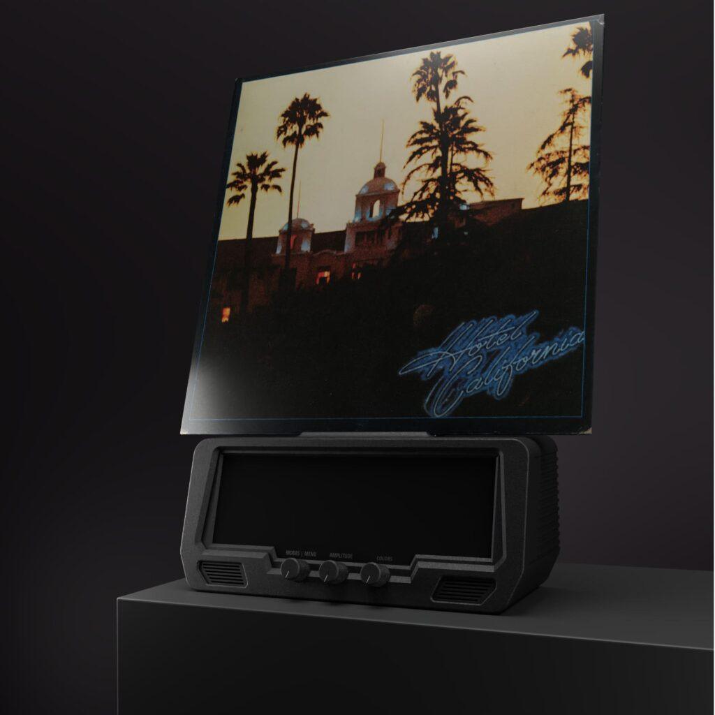 A vinyl record of Hotel California by the Eagles spins on a sleek black turntable with tonearm and stylus, set against a dark backdrop.
